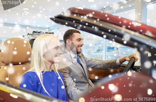 Image of happy couple sitting in car at auto show or salon