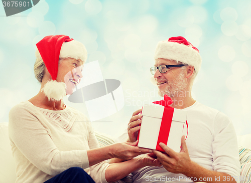 Image of happy senior couple with gift box at home