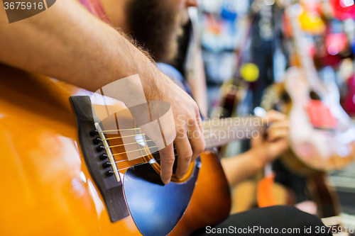 Image of close up of man playing guitar at music store