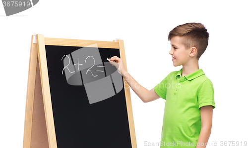 Image of happy boy solving math on school blackboard