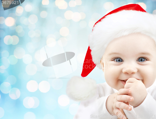 Image of happy baby in santa hat over blue holidays lights