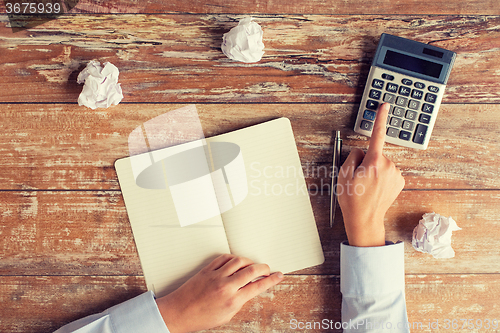 Image of close up of hands with calculator and notebook