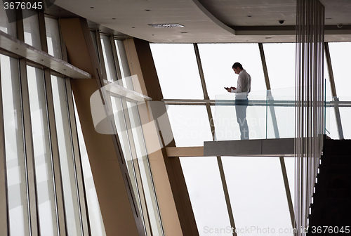 Image of young successful business man in penthouse apartment working on 