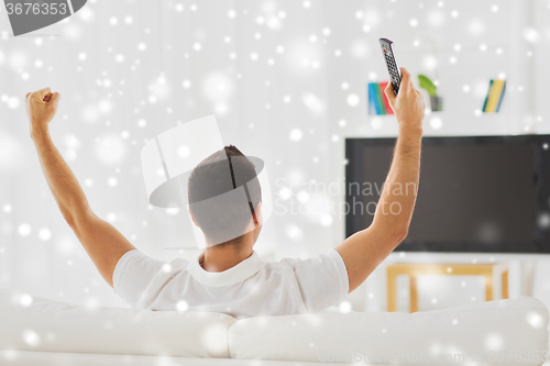 Image of man watching tv and supporting team at home