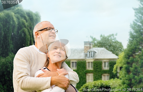 Image of senior couple hugging over living house background