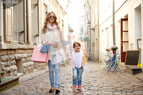 Image of happy mother and child with shopping bags in city