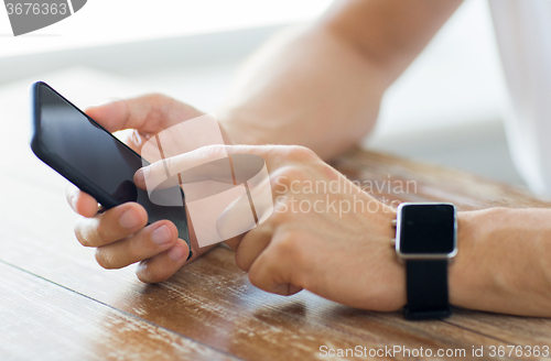 Image of close up of hands with smart phone and watch