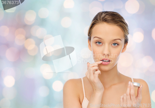 Image of young woman applying lip balm to her lips