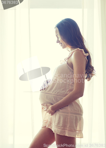 Image of happy pregnant woman with big bare tummy at home