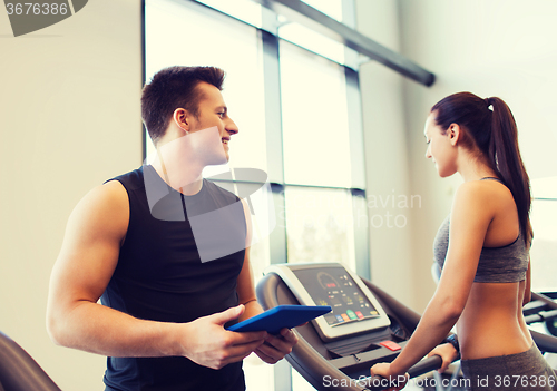 Image of happy woman with trainer on treadmill in gym