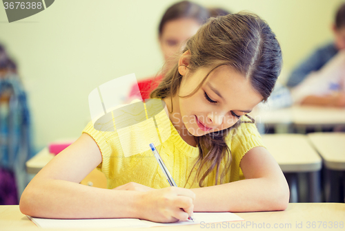 Image of group of school kids writing test in classroom