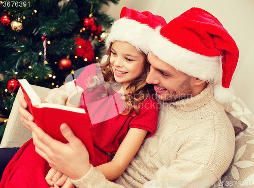 Image of smiling father and daughter reading book