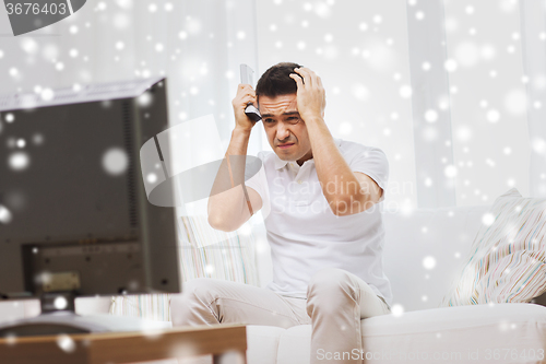 Image of disappointed man watching tv at home