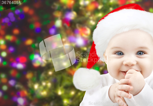 Image of happy baby in santa hat over christmas lights