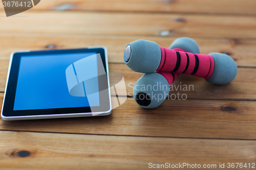 Image of close up of dumbbells and tablet pc on wood