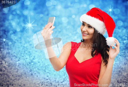 Image of woman in santa hat taking selfie by smartphone