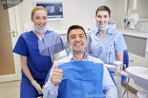 Image of happy female dentists with man patient at clinic