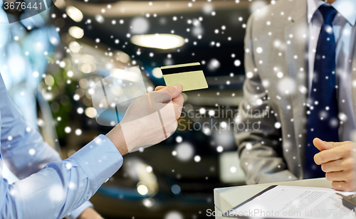 Image of customer giving credit card to car dealer in salon