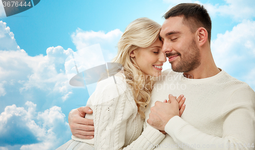 Image of happy couple cuddling over blue sky and clouds