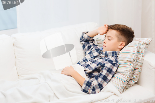 Image of ill boy lying in bed and suffering from headache