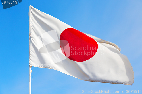 Image of japanb waving flag in the blue sky  and wave