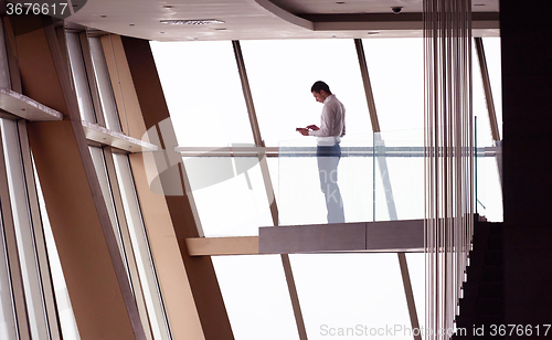 Image of young successful business man in penthouse apartment working on 