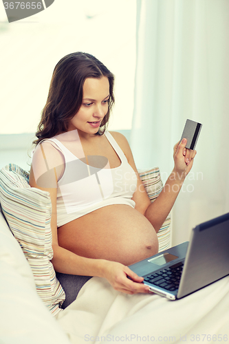 Image of pregnant woman with laptop and credit card at home