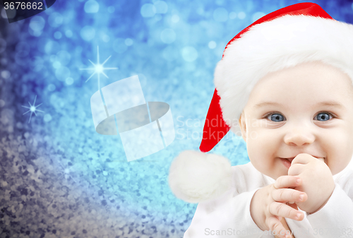 Image of happy baby in santa hat over blue holidays lights