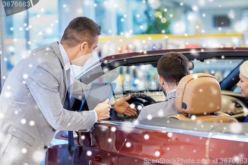 Image of happy couple with car dealer in auto show or salon