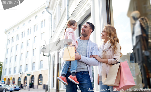 Image of happy family with child and shopping bags in city