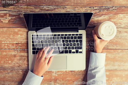 Image of close up of female hands with laptop and coffee