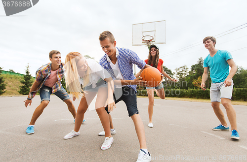 Image of group of happy teenagers playing basketball