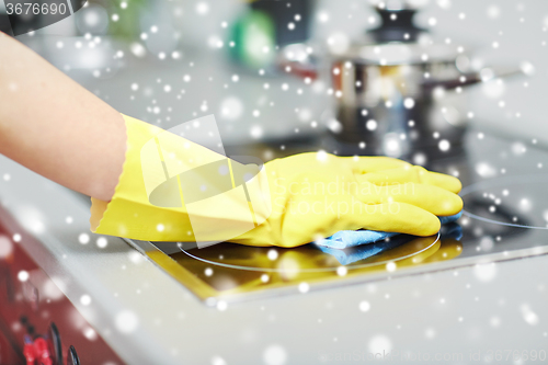 Image of close up of woman cleaning cooker at home kitchen