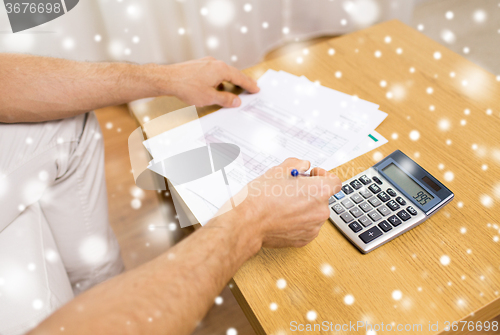Image of close up of man with papers and calculator at home