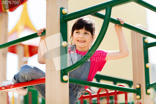 Image of happy little girl climbing on children playground