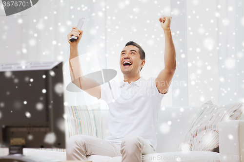 Image of smiling man watching sports at home