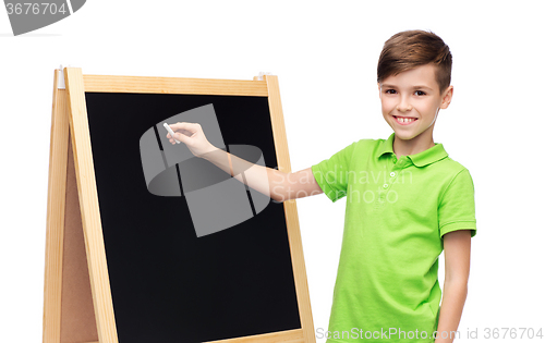 Image of happy boy with chalk and blank school blackboard