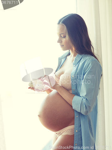 Image of happy pregnant woman with big bare tummy at home