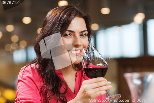 Image of smiling woman drinking red wine at restaurant