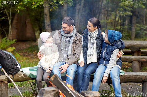 Image of happy family sitting on bench at camp fire
