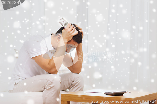 Image of man with money and calculator at home