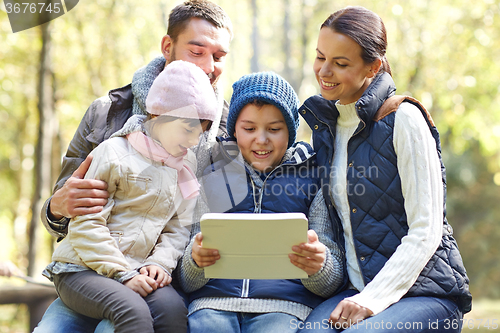 Image of family sitting on bench with tablet pc at camp