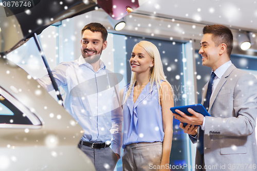 Image of happy couple with car dealer in auto show or salon