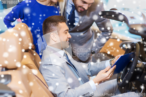 Image of happy couple with car dealer in auto show or salon