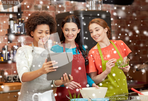 Image of happy women with tablet pc cooking in kitchen