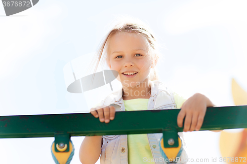 Image of happy little girl climbing on children playground