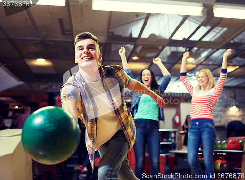 Image of happy young man throwing ball in bowling club