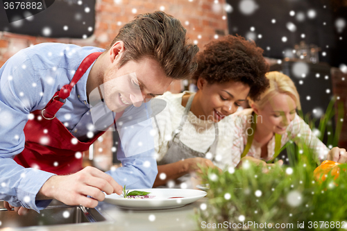Image of happy friends cooking and decorating dishes