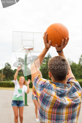 Image of group of happy teenagers playing basketball