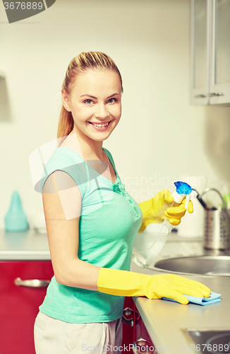 Image of happy woman cleaning table at home kitchen